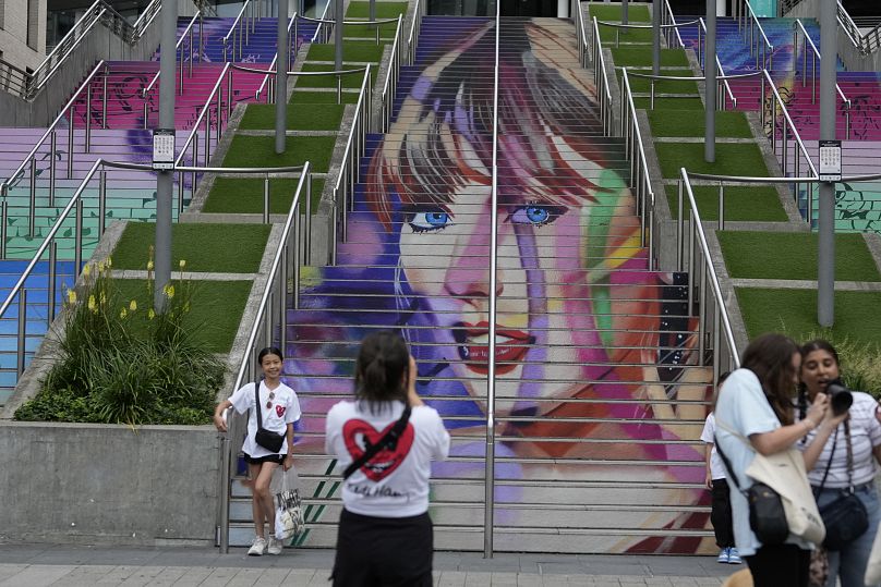 Fani pozują przy portrecie Taylor Swift namalowanym na schodach na stadionie Wembley w Londynie - środa 14 sierpnia