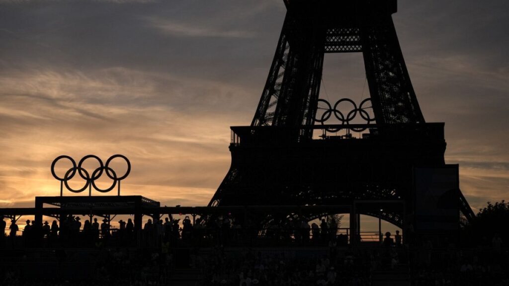 Spectators watch a quarterfinal beach volleyball match between Australia and Switzerland at sunset at Eiffel Tower Stadium at the 2024 Summer Olympics, Tuesday, Aug. 6, 2024