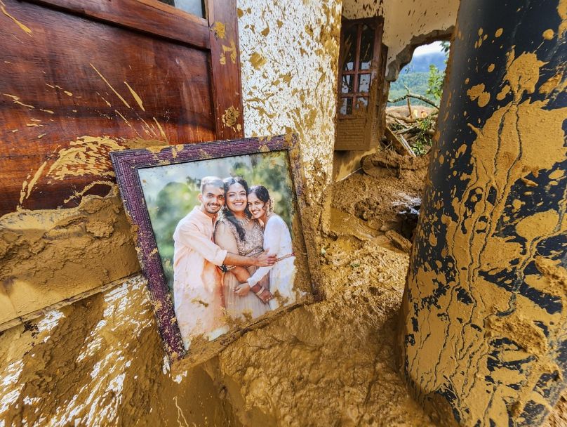 Oprawione zdjęcie leży częściowo pokryte błotem przy uszkodzonym domu po osuwiskach, które nawiedziły pagórkowate wioski w dystrykcie Wayanad w stanie Kerala w Indiach, wtorek, 30 lipca 2024 r.