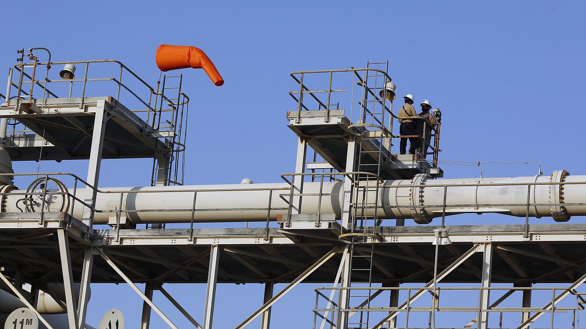 Workers stand on a platform at a Saudi Aramco oil separator processing facility in Abqaiq (file photo)