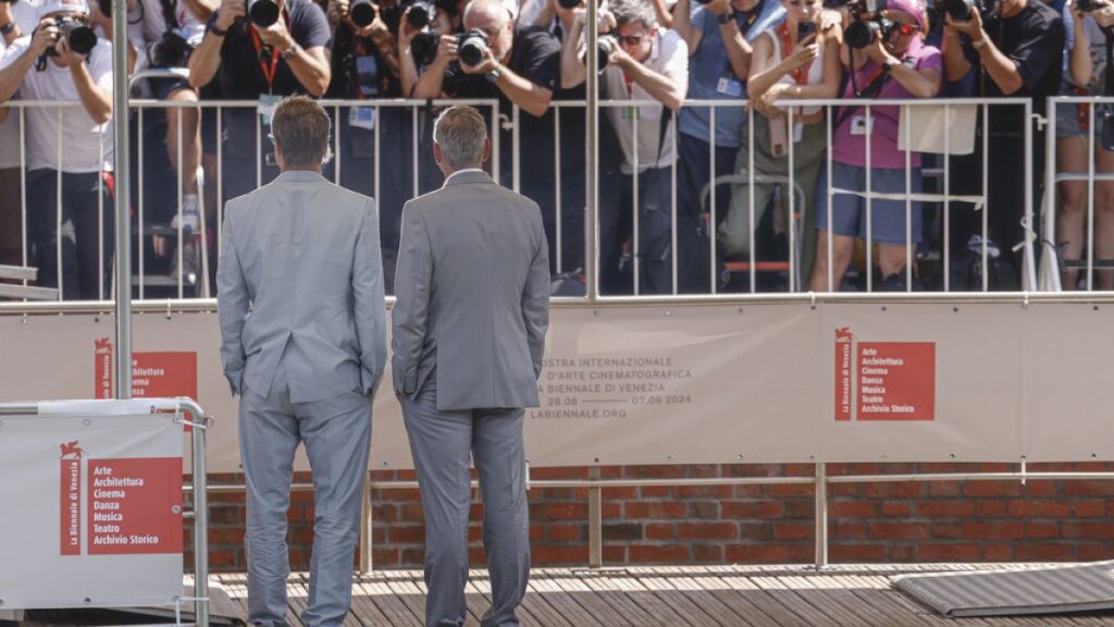 Brad Pitt, left, and George Clooney pose for photographers upon arrival for the press conference of the film