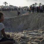 Palestinians look at the destruction after an Israeli airstrike on a crowded tent camp in Muwasi.