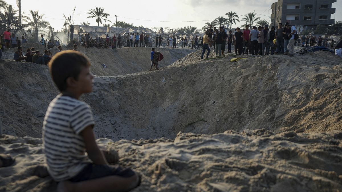 Palestinians look at the destruction after an Israeli airstrike on a crowded tent camp in Muwasi.