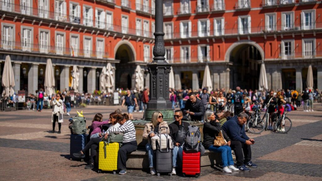 Tourists sit on a public bench in the Plaza Mayor square in downtown Madrid, Spain, Monday, April 29, 2024.