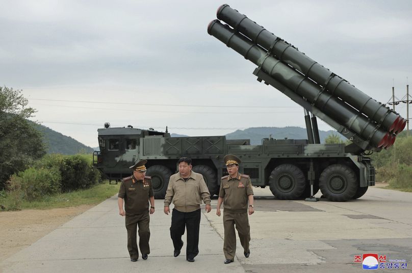 Kim Dzong Un (w środku) z innymi urzędnikami przechadza się w pobliżu nowej wyrzutni rakiet kal. 600 mm, która ma znajdować się w nieujawnionej lokalizacji w Korei Północnej.