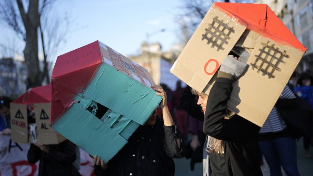 Two young women wear cardboard houses over their heads during a demonstration protesting Portugal