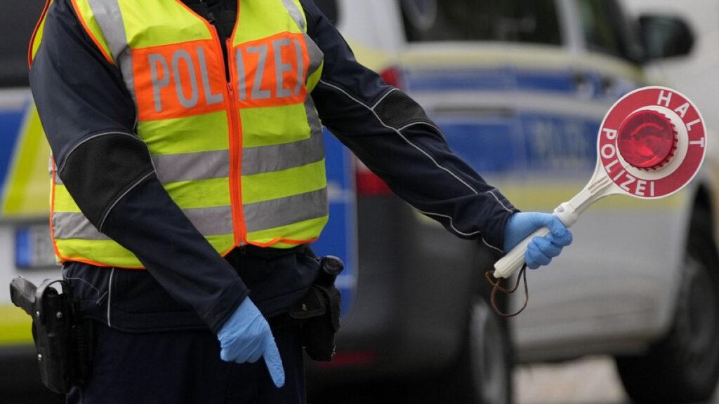 A German federal police officer stops cars and trucks at a border crossing point