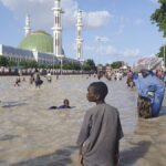 People walk through floodwaters following a dam collapse in Maiduguri, Nigeria, Tuesday Sept 10, 2024.