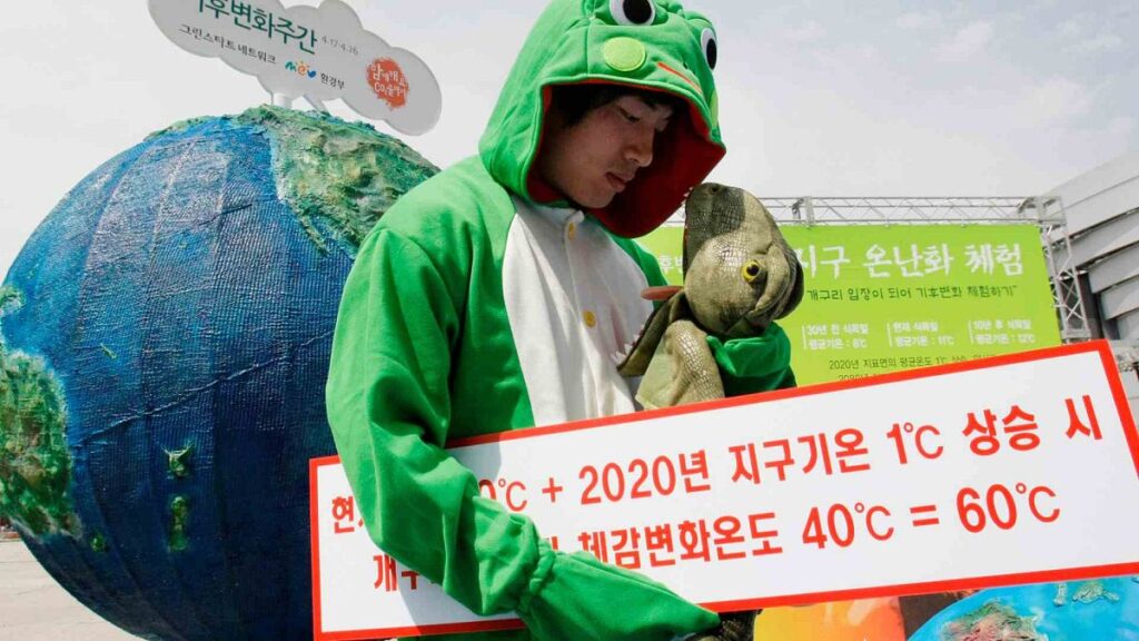 A South Korean environment activist wearing frog costume walks past a global warming performance in front of Seoul City Hall during a clean air campaign in Seoul, South Korea,