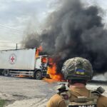 A police officer looks at a burning Red Cross vehicle that was destroyed in a Russian strike in Donetsk, September 12, 2024