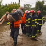 A rescuer carries an old man in Pechea, Romania, Saturday, Sept. 14, 2024 after torrential rainstorms left scores of people stranded in flooded areas.