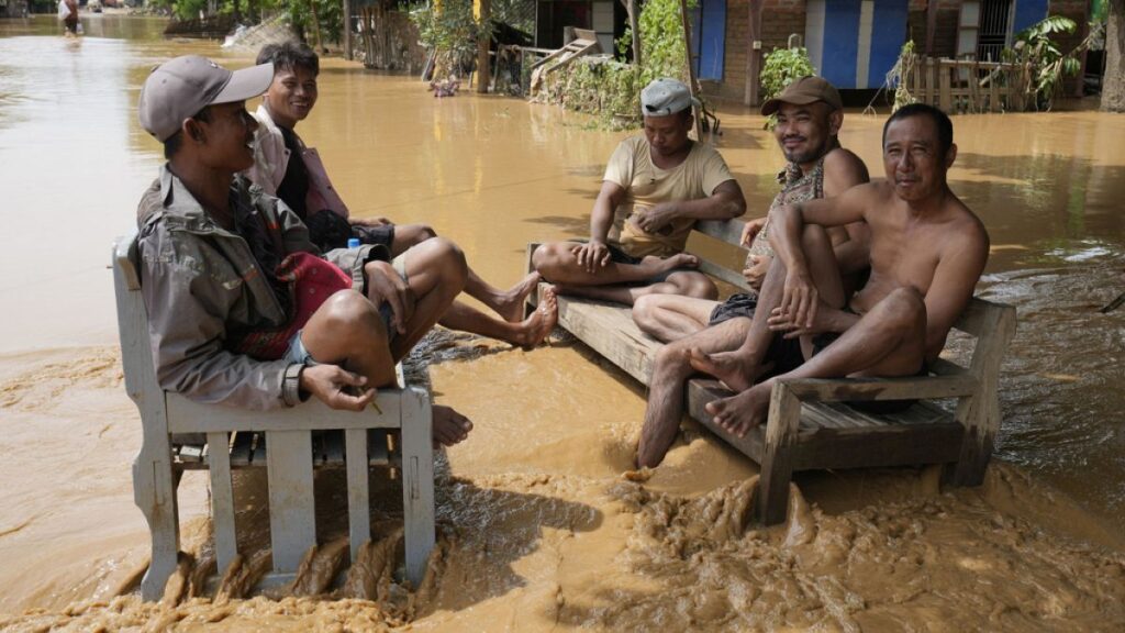 Local residents sit on a bench on a flooded road in Naypyitaw, Myanmar, Saturday, Sept. 14, 2024