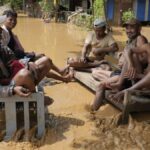 Local residents sit on a bench on a flooded road in Naypyitaw, Myanmar, Saturday, Sept. 14, 2024