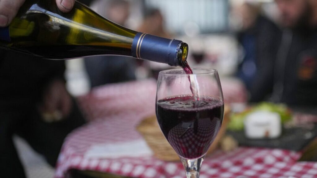 FILE: A customer pours a glass of Beaujolais Nouveau wine in a restaurant of Boulogne Billancourt, outside Paris, Thursday, Nov. 18, 2021.