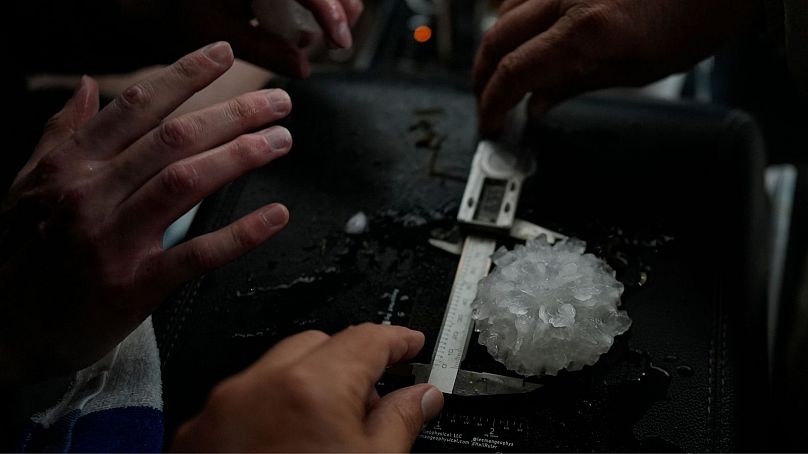 Naukowcy mierzą duże grad w kształcie róży między przednimi siedzeniami pojazdu Husky Hail Hunter podczas operacji ICECHIP, 6 czerwca. 